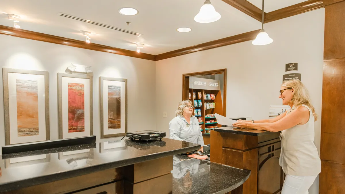 A welcoming lobby area with a reception desk, modern artwork, and a snack area, creating a friendly first impression. The space hints at convenient guest services and the effortless, resort-like touch described in the section, perfect for welcoming families, couples, and business travelers alike.