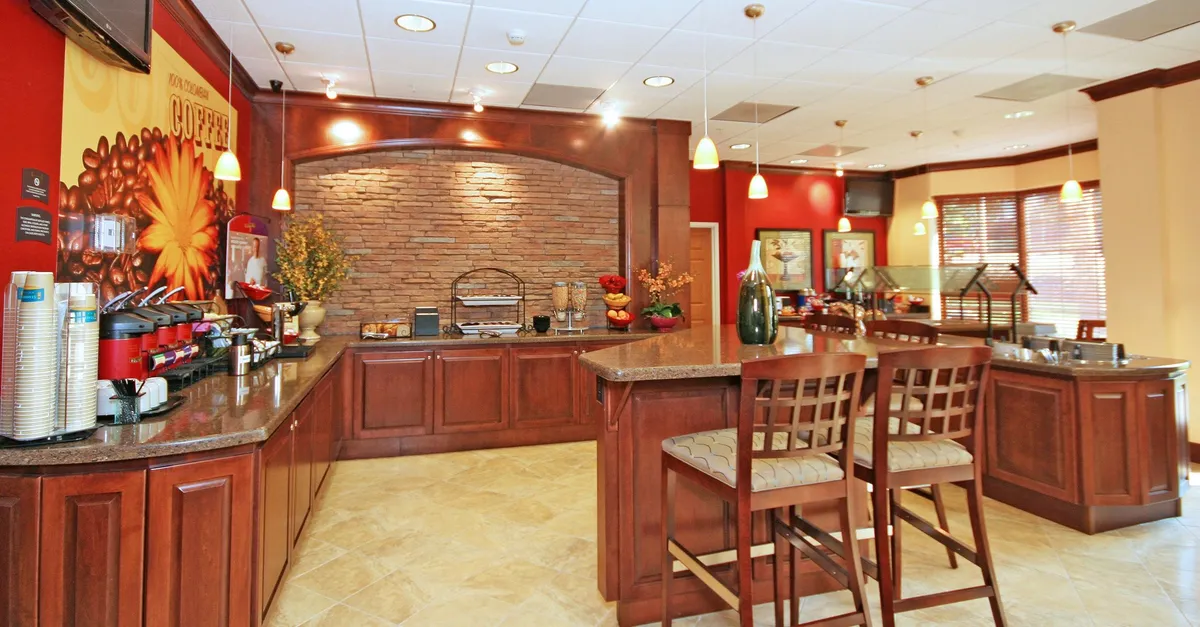 This image displays a stylish coffee station with a stone wall backdrop and a bar counter, inviting guests to grab a fresh cup of coffee or socialize in a casual, welcoming setting. The arrangement suggests a communal atmosphere perfect for starting the day or enjoying a relaxing break.