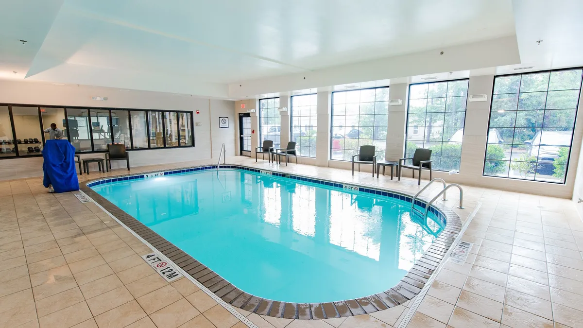 This image features an inviting indoor swimming pool, flanked by large windows that let in natural light and a cozy seating area for relaxation. The tranquil atmosphere is ideal for unwinding after a busy day or enjoying a leisurely swim, and the pool's design suggests it's a welcoming space for both individuals and families.